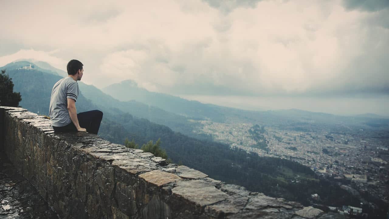 Young Man Sitting on Stone Wall - PersonalProfitability.com