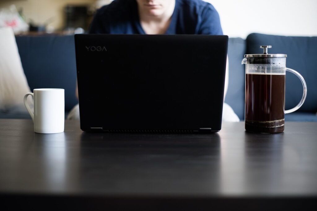 A laptop and coffee at a home workspace, the basic setup for how to start a blog to make money