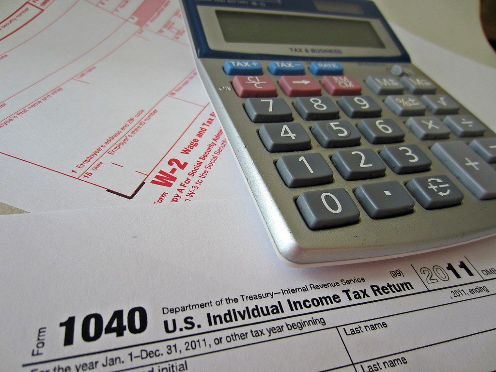 Form 1040 tax return and a calculator, illustrating when to elect S corp status for your LLC
